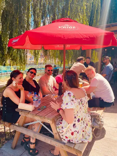 Colleagues at a riverside pub garden under a red parasol.