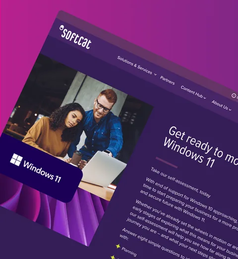 A Softcat Windows 11 page with two colleagues at a laptop, at an angle